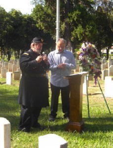 Brad Schall (left) speaks at a headstone dedication ceremony